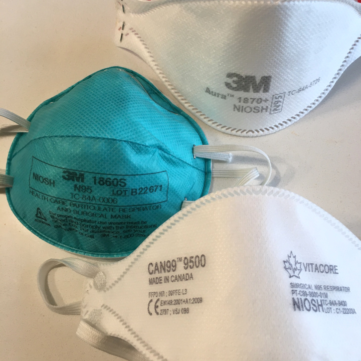 A photo of three white and blue N95 respirators.