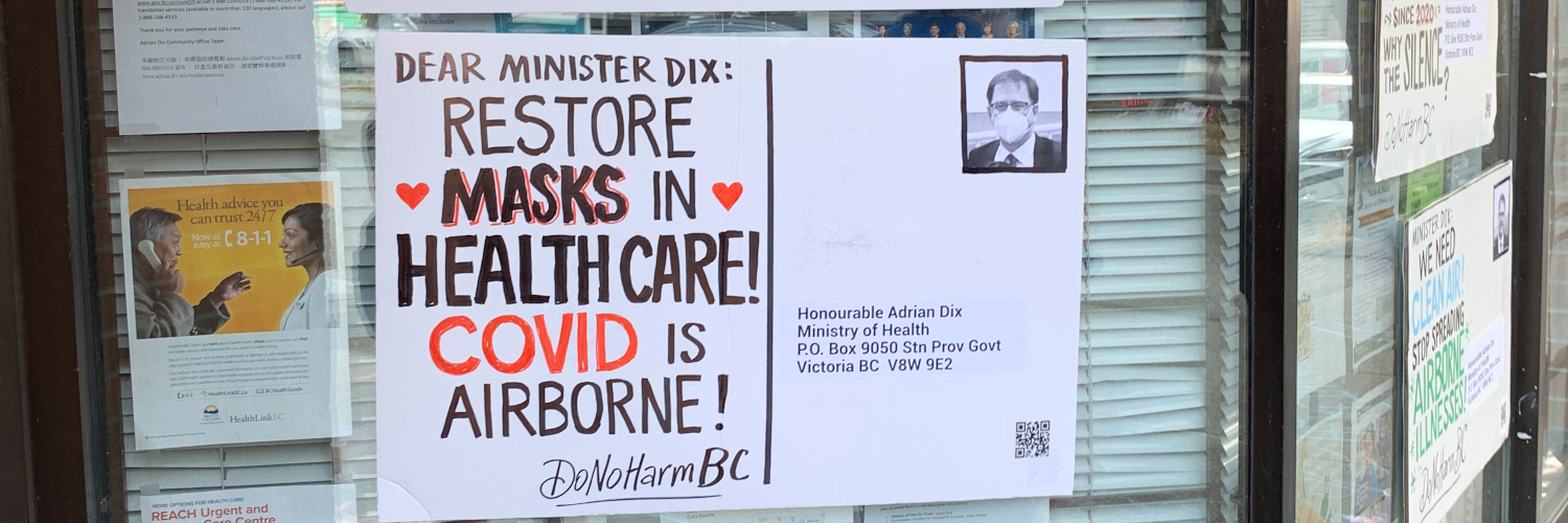 Une carte postale surdimensionnée apposée sur la fenêtre du bureau du député d’Adrian Dix. La carte postale se lit comme suit : « Dear Minister Dix: Restore Masks in Healthcare! Covid is Airborne! DoNoHarm BC. » À la place d’un timbre-poste, le ministre de la Santé Adrian Dix porte un masque respiratoire. Photo par DoNoHarm BC.