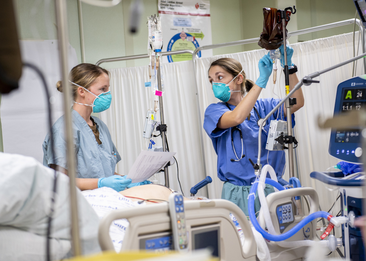 Le lieutenant (grade junior) Kayla Marthy, de Long Island, New York (à gauche), et le lieutenant (grade junior) Brianna Garcia, de St. Petersburg, Floride, traitent un patient dans l’unité de soins intensifs à bord du navire-hôpital USNS Mercy (T-AH 19), le 13 avril 2020. Photo de l’U.S. Navy par Ryan M. Breeden, spécialiste des communications de masse de 2e classe.